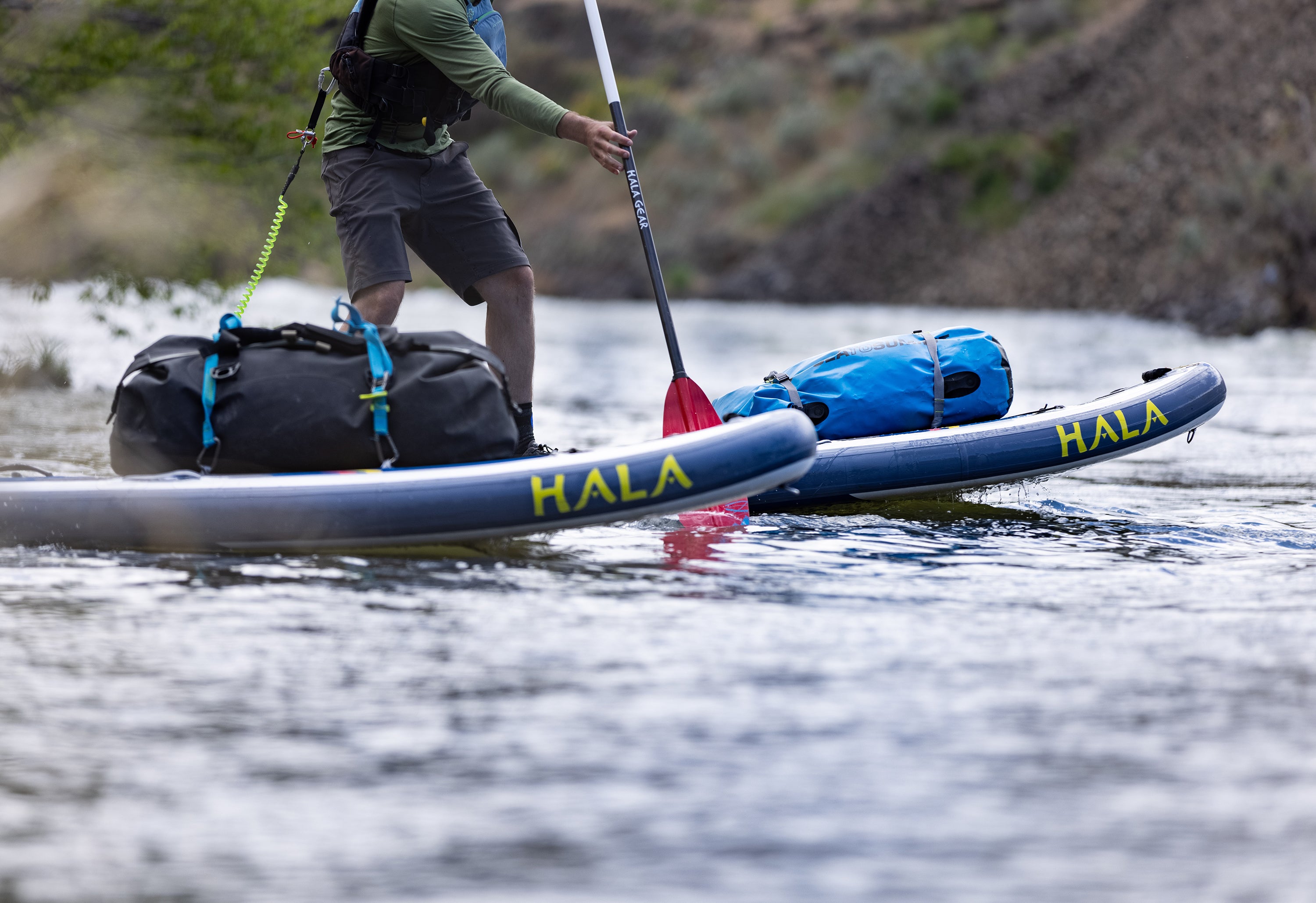 Query successful A pair of Hala inflatable stand-up paddleboards (SUPs) are loaded with gear for a multi-day river trip.