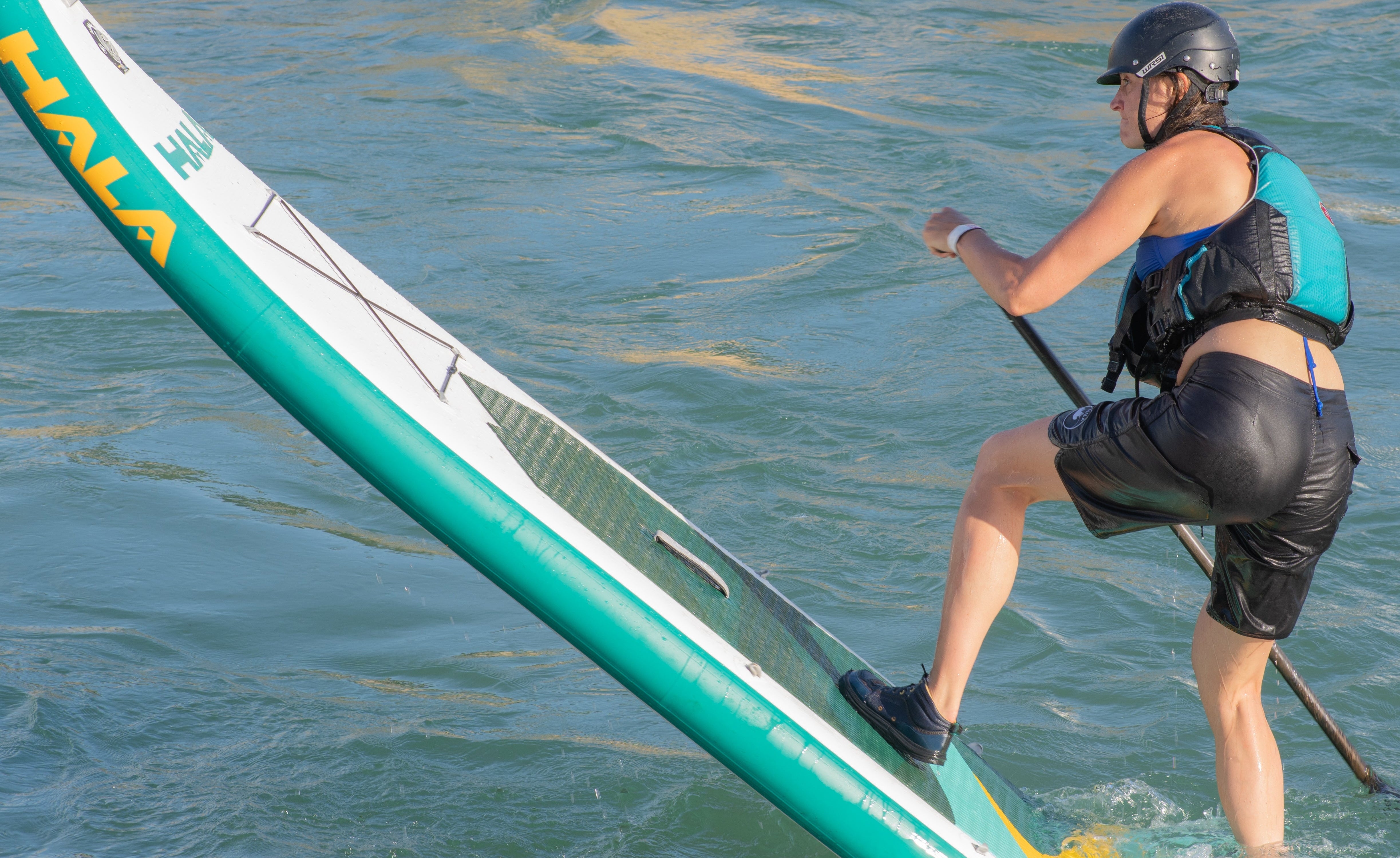 Person paddleboarding on a Hala board in the water - pivoting on the tail of the Hala Straight Up.