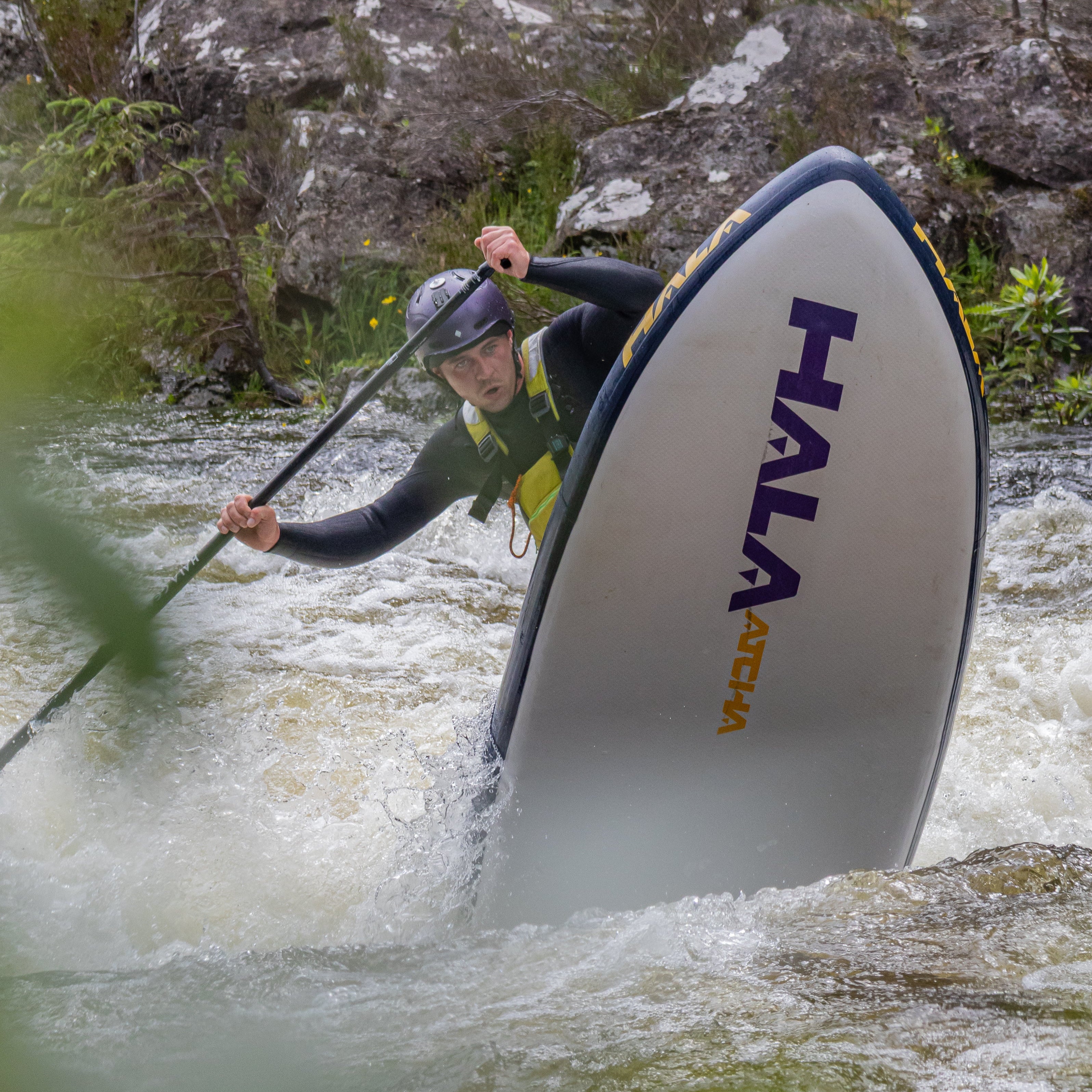 Aggressively stand-up paddleboarding down whitewater rapids