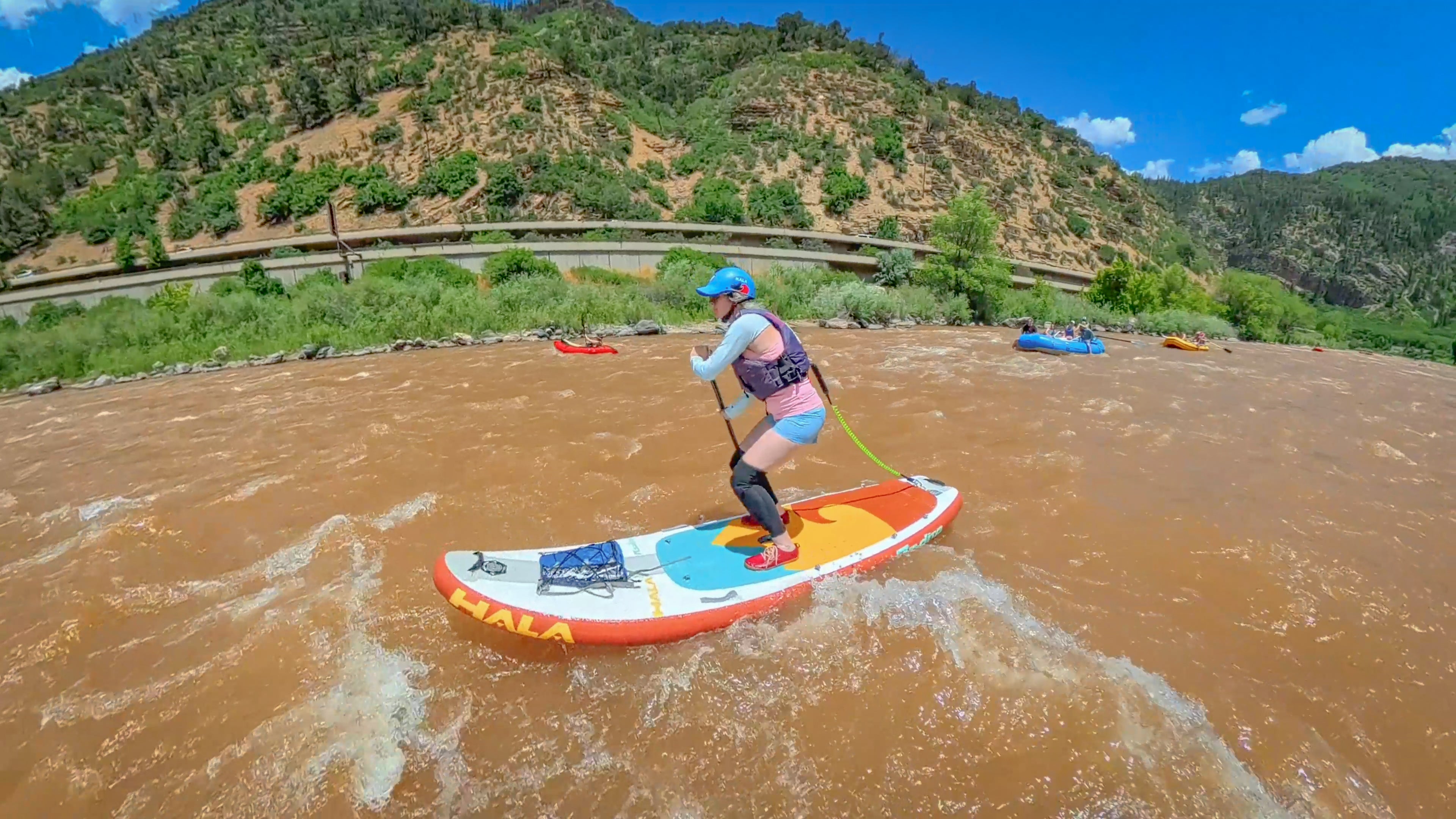 stand-up paddleboarder is navigating a muddy, brown river
